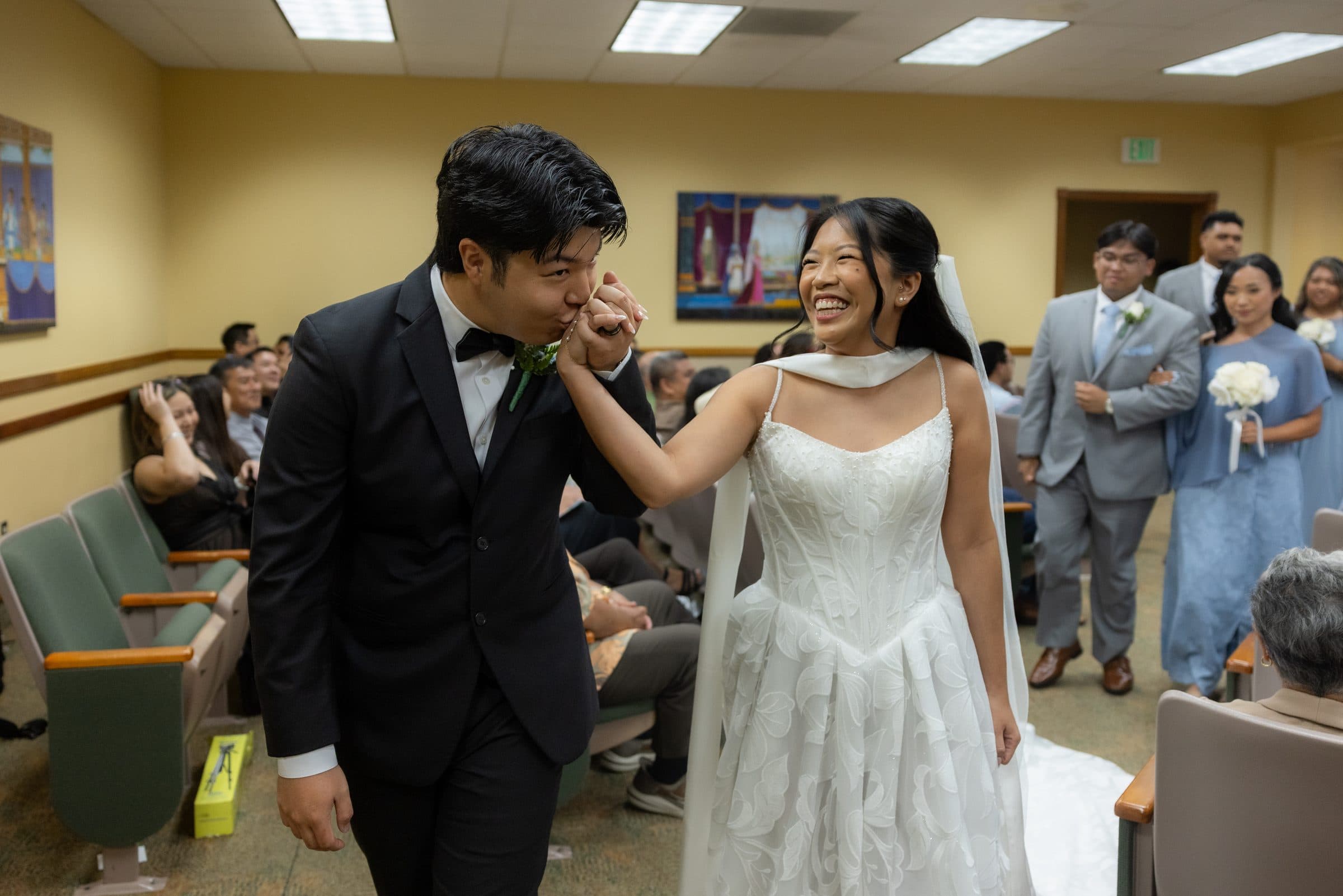 Mia and Brennan walk back down the aisle, smiling, past their wedding party.