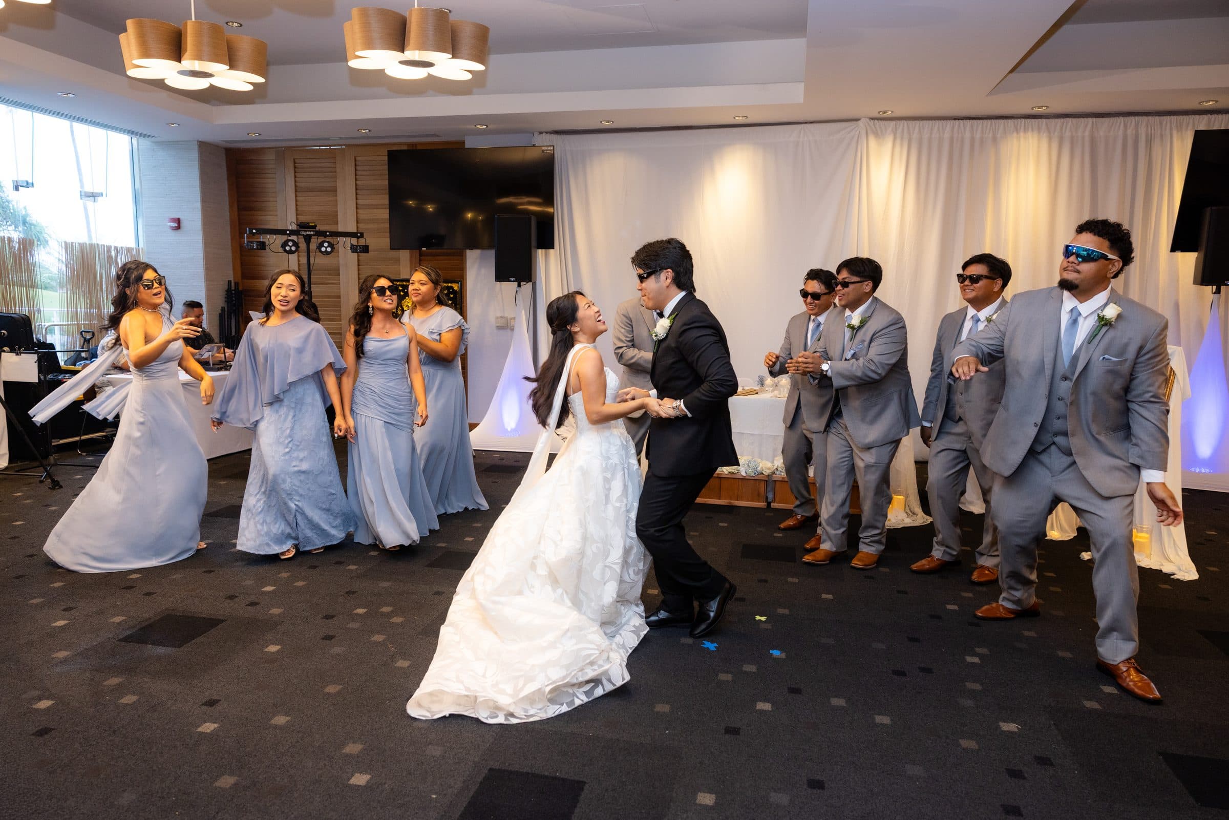 Mia and Brennan dance in the middle of the floor with their wedding party around them.