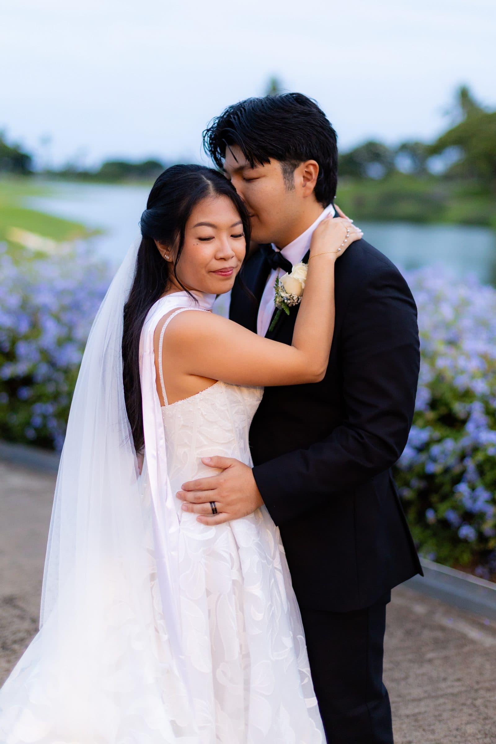 Brennan kisses Mia's forehead in the evening light by the water.