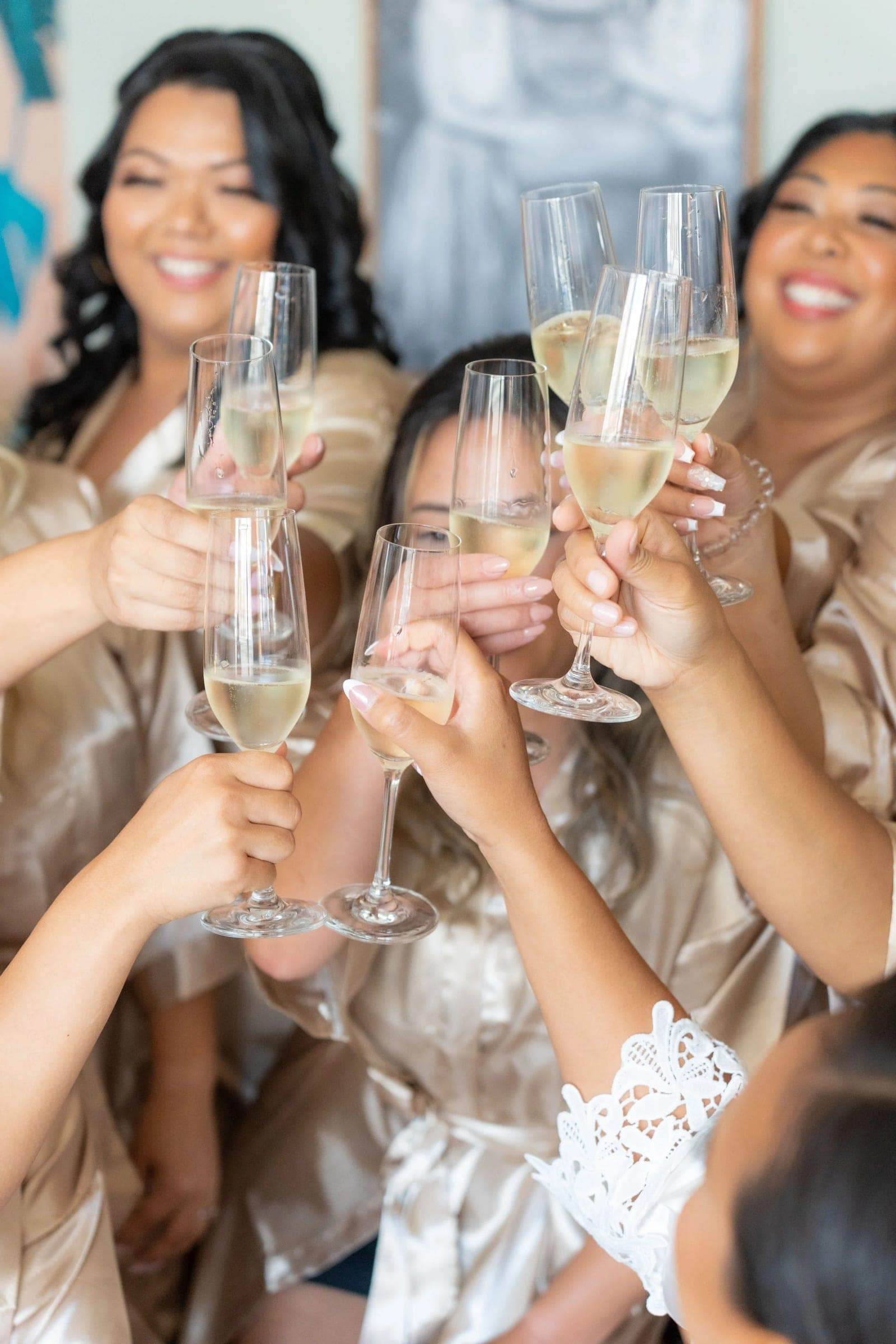 Bridesmaids raise champagne glasses together while getting ready.